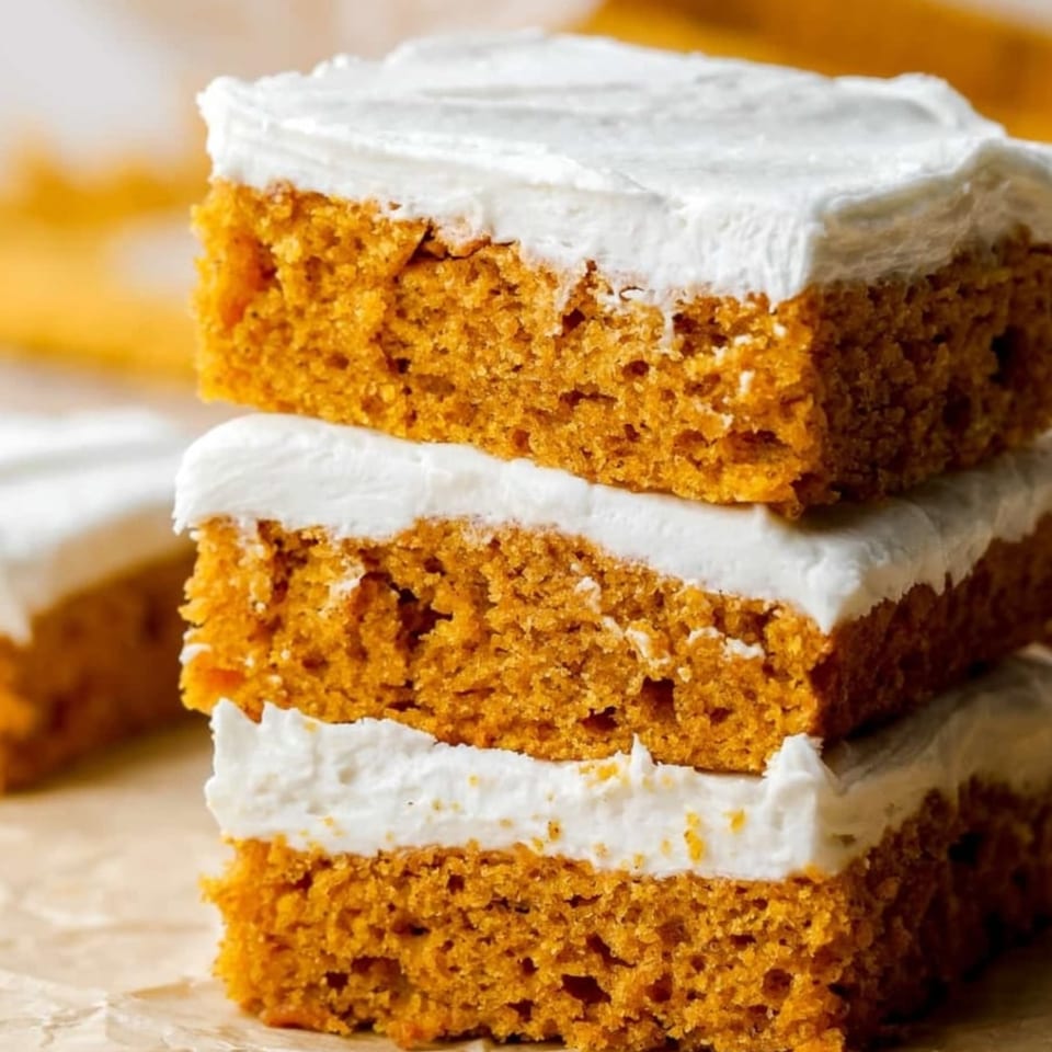 Stack of three vegan pumpkin cake squares with white frosting from Essential Smoothies Cafe.